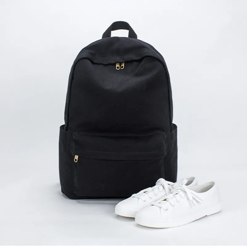 Front view of a custom black rucksack next to white sneakers