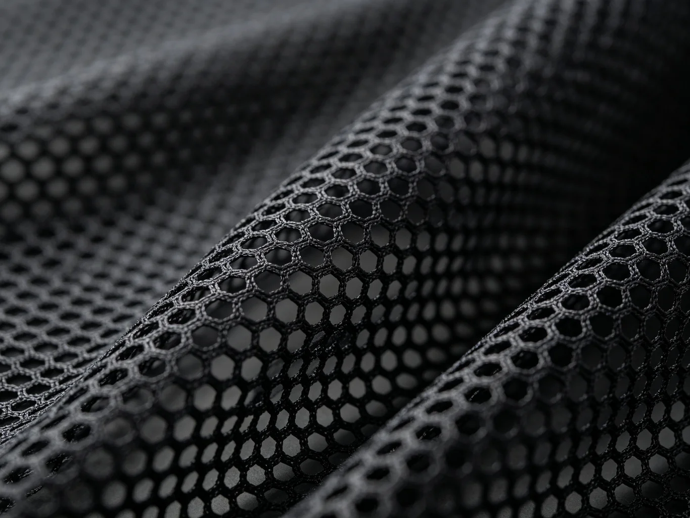 Black 3D air mesh netting fabric showing hexagonal honeycomb hole pattern