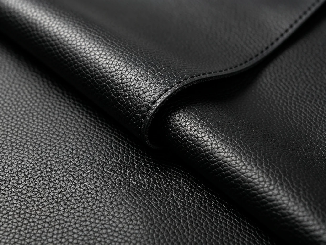 Matte black PU faux leather texture showing uniform embossed pebbled grain pattern